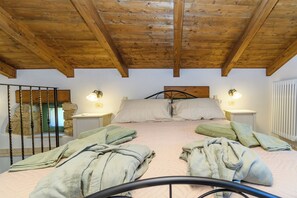 A bedroom with a wooden ceiling, two bedside tables with lamps, a bed with pillows and folded towels, and a stone wall. - House Barba Frane (Vizinada)