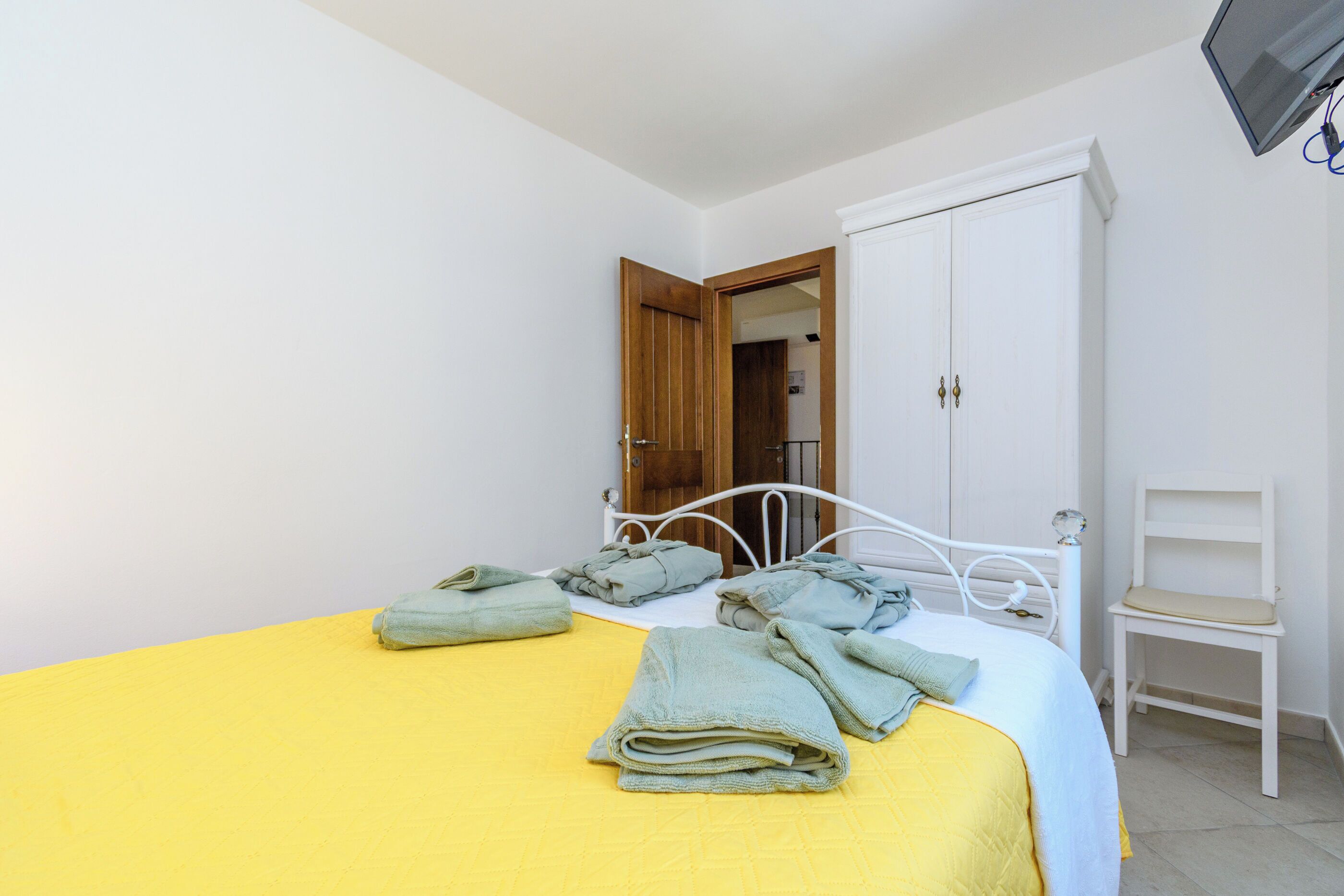 Ein Schlafzimmer mit einem Bett, einem Kleiderschrank, einem Sessel und einem Fernseher.