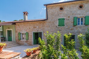 A stone building with green shutters, a chimney, and potted plants. - House Barba Frane (Vizinada)