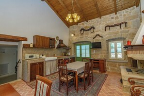 A rustic kitchen with stone walls, wooden furniture, and a chandelier. - House Barba Frane (Vizinada)