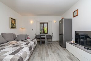 A bedroom with a bed, a desk, a chair, a refrigerator, and a television. - Apartment Leona's Paradise (Opatija)
