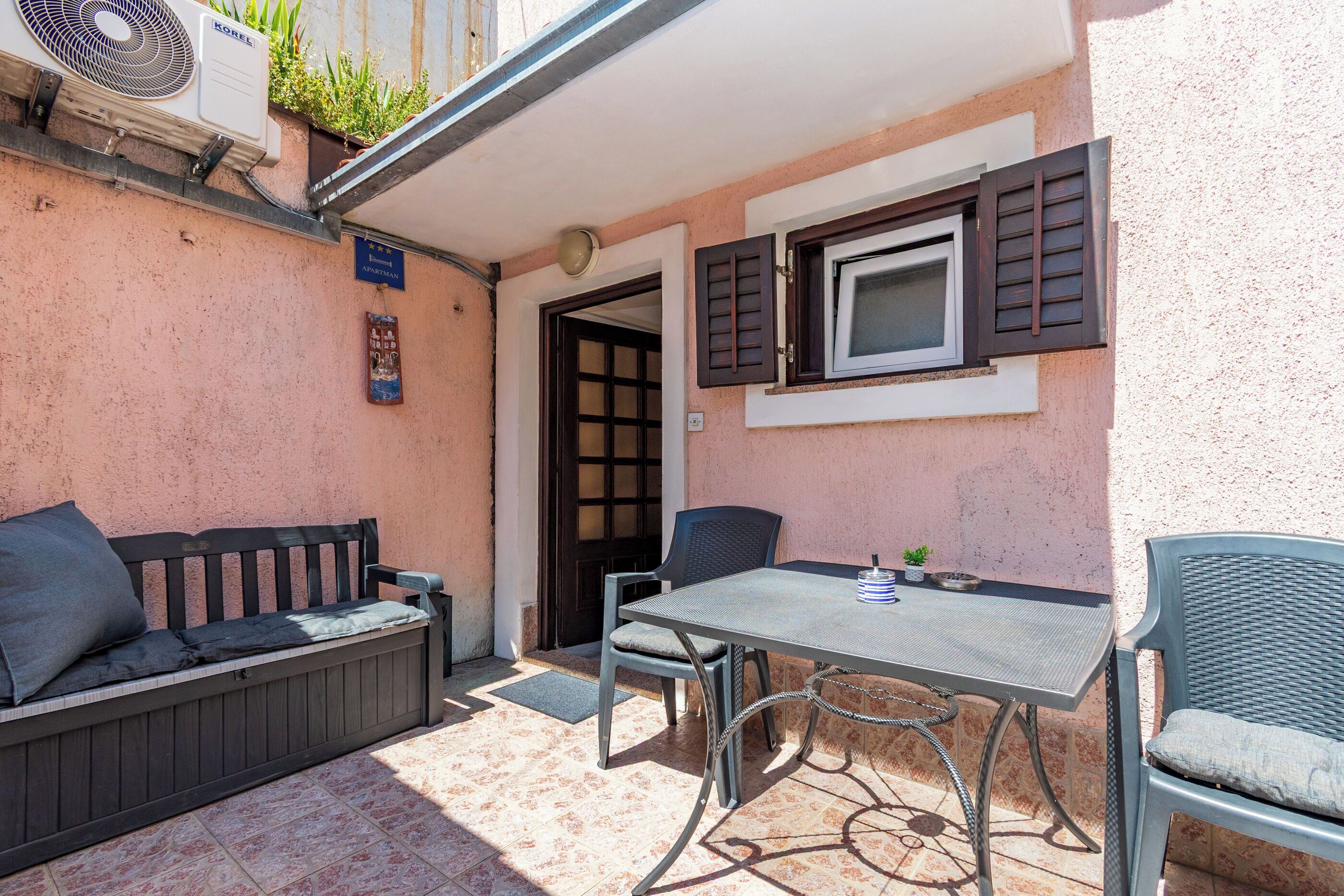 A patio with a table, chairs, a bench, and an air conditioning unit.