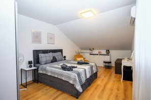 Une chambre à coucher comprenant un lit, des tables de chevet, un ventilateur fixé au mur et un luminaire au plafond.