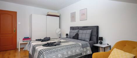 A bedroom with a bed, a wardrobe, a chair, and a bedside table.
