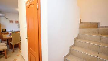Eine Treppe mit Geländer und einer Holztür mit Messinggriffen.