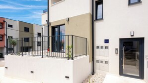 Un bâtiment moderne doté d’un balcon, d’une porte et d’une enseigne indiquant « Chambre d’hôtes ».