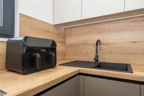 A kitchen with a built-in espresso machine, a sink, and wooden cabinetry. - Apartment Seaview Terrace (Podstrana)