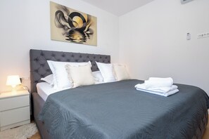 A neatly made bed with a grey headboard, white pillows, and a grey bedspread. - Apartment Seaview Terrace (Podstrana)