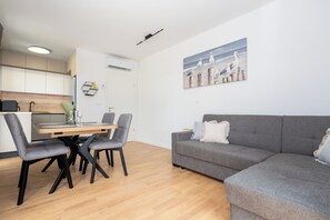 A modern living room with a grey sofa, a dining table with chairs, and a painting of seagulls on the wall. - Apartment Seaview Terrace (Podstrana)