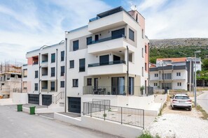A multi-story residential building with balconies, a garage, and a car parked in front. - Apartment Seaview Terrace (Podstrana)