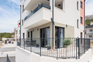 A modern apartment building with balconies, a covered outdoor seating area, and a landscaped garden. - Apartment Seaview Terrace (Podstrana)