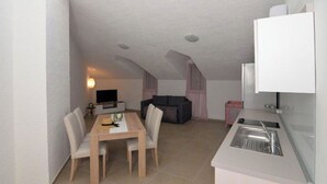 A compact living space with a dining area, kitchenette, and seating area. - Apartment Nikola Centar (Biograd na Moru)