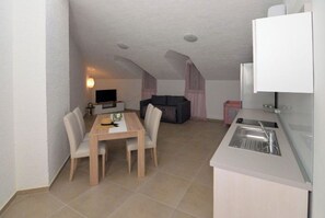 A compact living space with a dining area, kitchenette, and seating area. - Apartment Nikola Centar (Biograd na Moru)