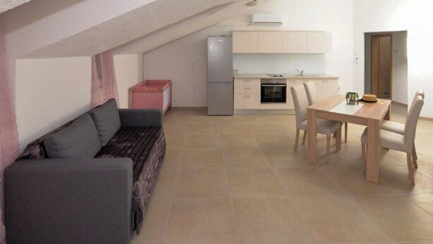 A compact living space with a sofa, a dining table, and a kitchenette. - Apartment Nikola Centar (Biograd na Moru)