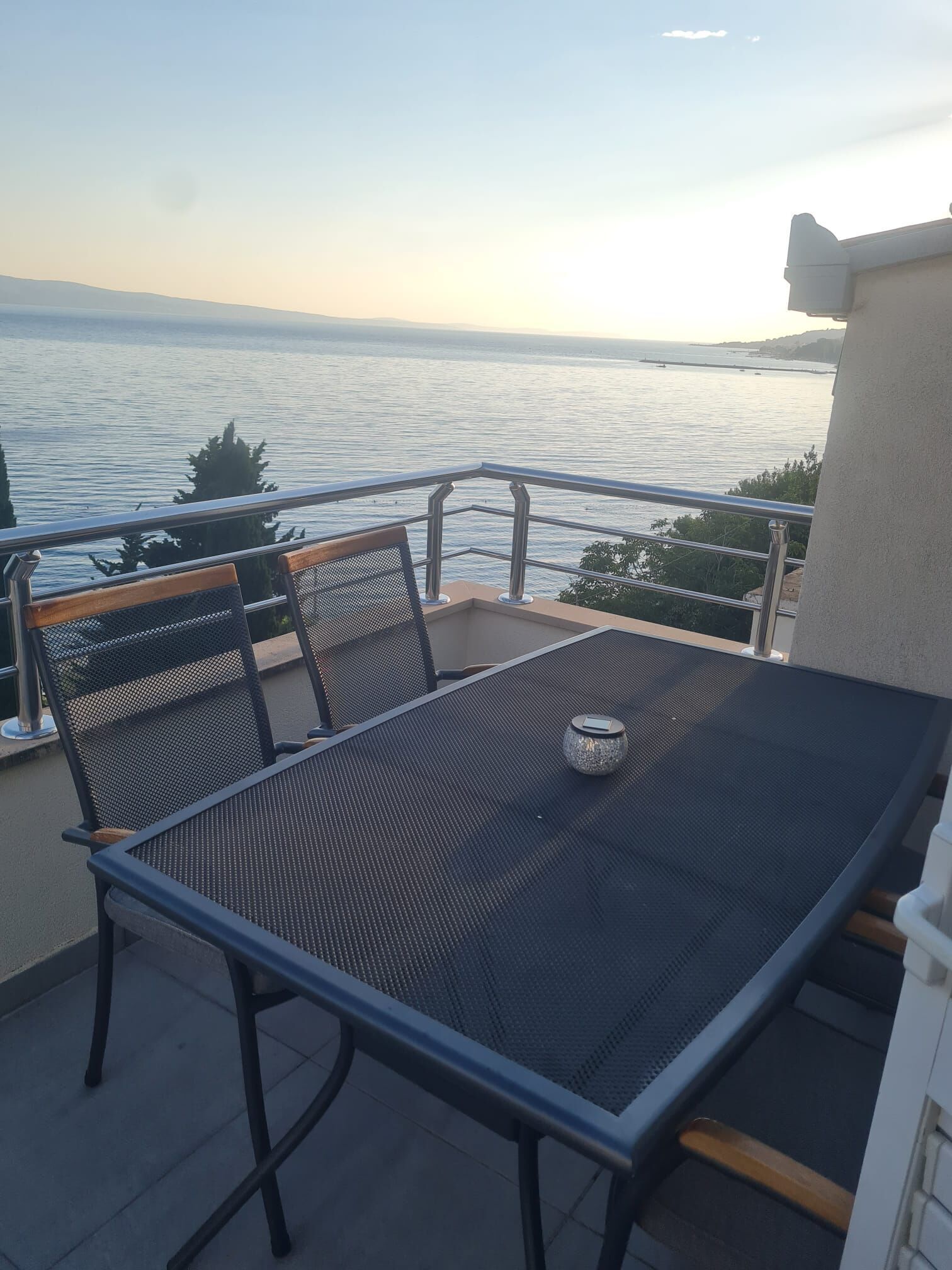 Een balkon met tafel en stoelen met uitzicht op een wateroppervlak.