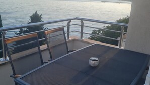 Un balcón con mesa y sillas que da a una masa de agua.
