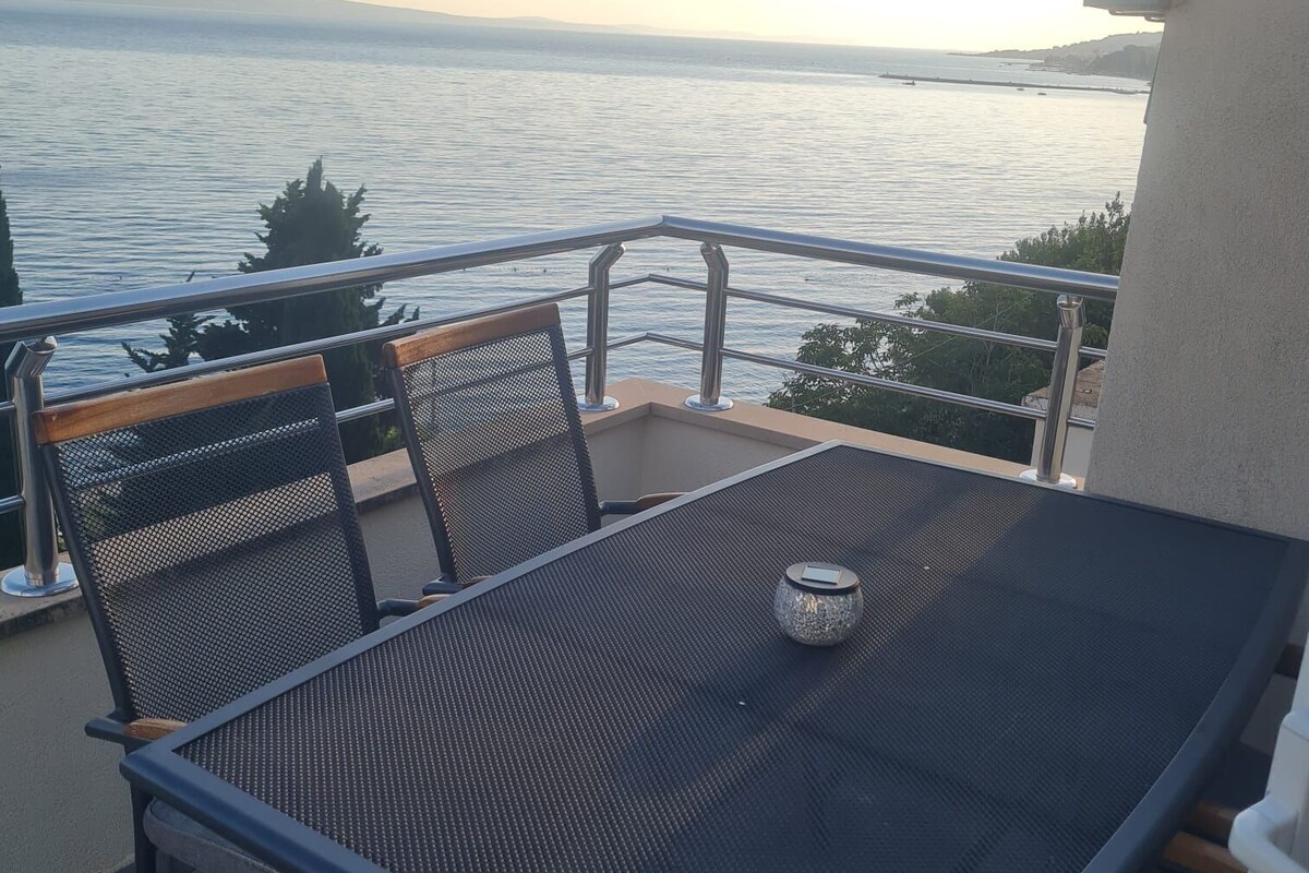 A balcony with a table and chairs overlooking a body of water.
