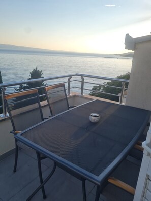 A balcony with a table and chairs overlooking a body of water. - Apartments Damir (Omis)