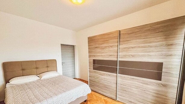 A bedroom with a bed, a wardrobe, and a door. - Apartment Franky (Crikvenica)