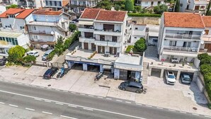 A multi-story residential building with a garage, parked cars, and a visible driveway. - Apartment Franky (Crikvenica)
