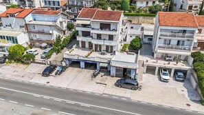 Ein mehrgeschossiges Wohnhaus mit Garage, parkenden Autos und einer sichtbaren Auffahrt.