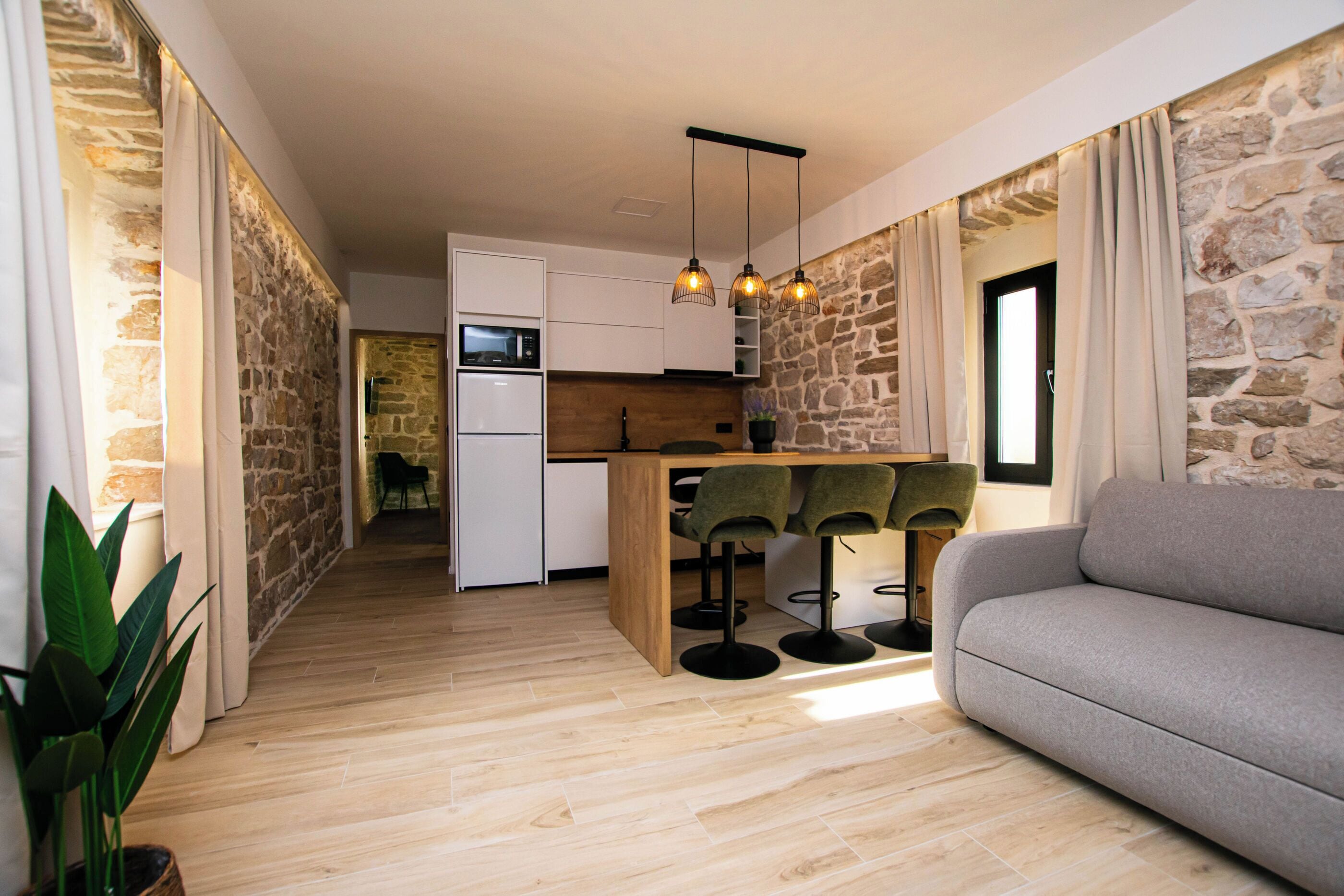 A modern kitchen with white cabinets, a wooden island, and bar stools.