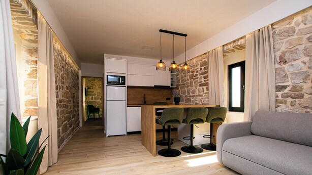 A modern kitchen with white cabinets, a wooden island, and bar stools. - Apartment Blue Wind (Tkon)