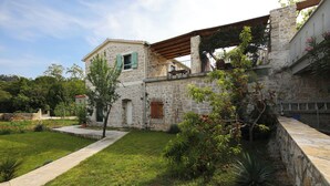 A stone building with a balcony, a small tree, and a well-maintained lawn. - Apartment Blue Wind (Tkon)