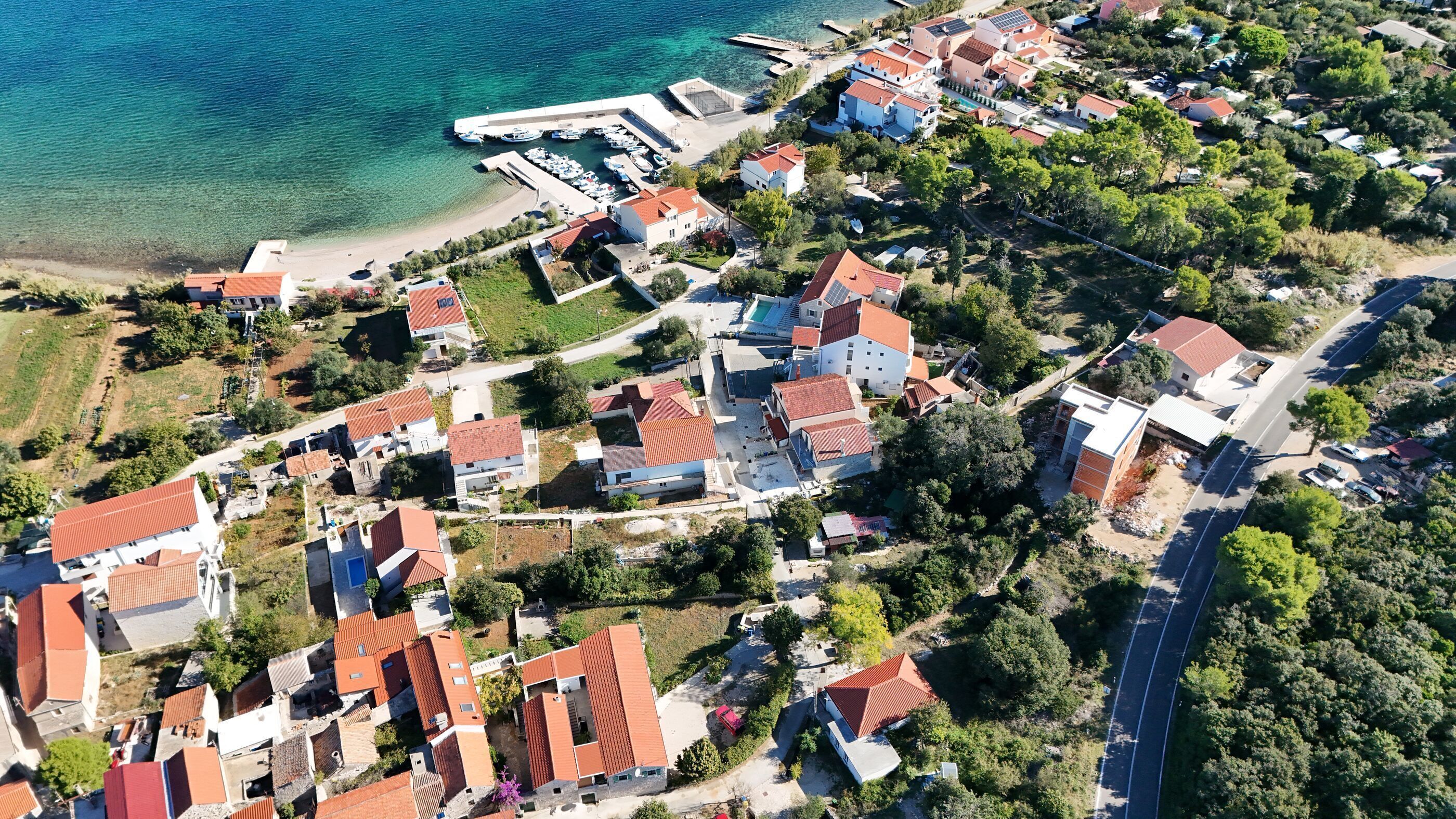 An aerial view of a coastal residential area with houses, a marina, and clear blue waters.
