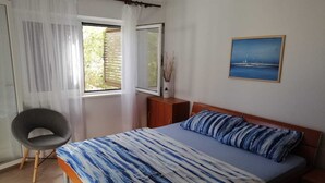 Ein Schlafzimmer mit einem Bett, einem Sessel, einem Fenster und einem Bild an der Wand.