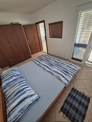 A bedroom with a bed, wardrobe, and a window with blinds. - Apartments Sepcevic (Murter-Kornati)