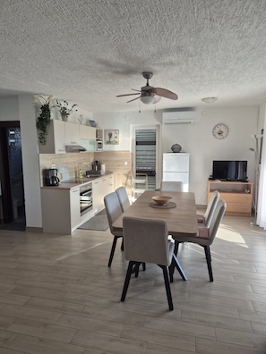 Une cuisine moderne avec un coin repas, comprenant une table avec des chaises, un ventilateur de plafond et un réfrigérateur.