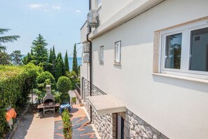 A building with a stone exterior, a window, and a view of the sea. - Apartment Nikol (Crikvenica)