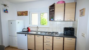 A compact kitchen with a dishwasher, a stove, a sink, and wooden cabinets. - Apartment Nikol (Crikvenica)