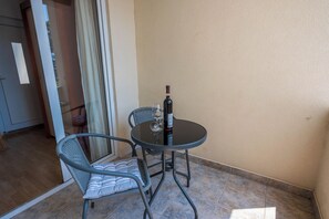 A small round table with two chairs, a bottle of wine, and a glass on the table. - Apartment Nikol (Crikvenica)