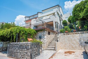 A modern two-story building with a stone staircase, a balcony, and a metal fence. - Apartment Nikol (Crikvenica)