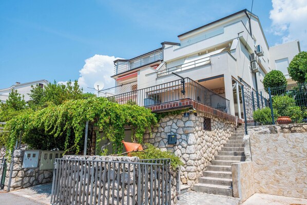 A multi-story building with a stone staircase leading to a balcony. - Apartment Nikol (Crikvenica)