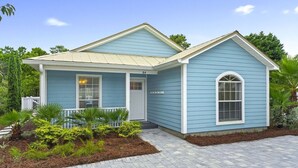 Ein zweigeschossiges Haus mit blauer Fassade, einer Veranda und einem kleinen Garten.