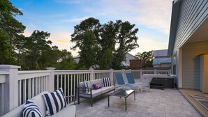 Ein Außenbereich mit Terrasse, einer Sofagruppe, Liegestühlen und einem Grill.