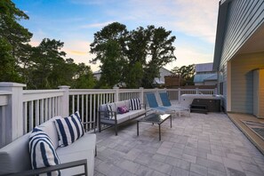 Ein Außenbereich mit Terrasse, einer Sofagruppe, Liegestühlen und einem Grill.