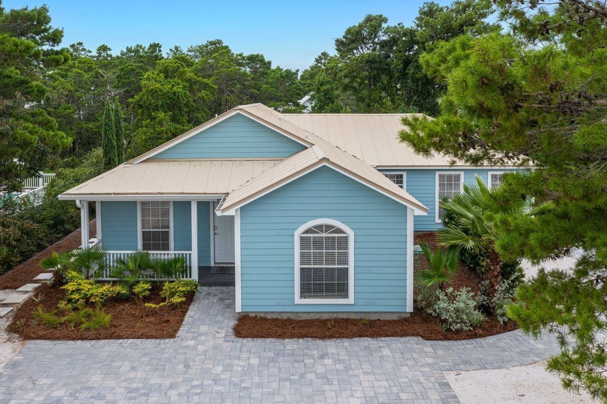 A two-story house with a gabled roof, a front porch, and a landscaped front yard.