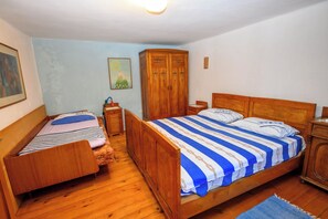 A room with two wooden beds, a wooden wardrobe, and a nightstand with a lamp. - House Arija (Novi Vinodolski)
