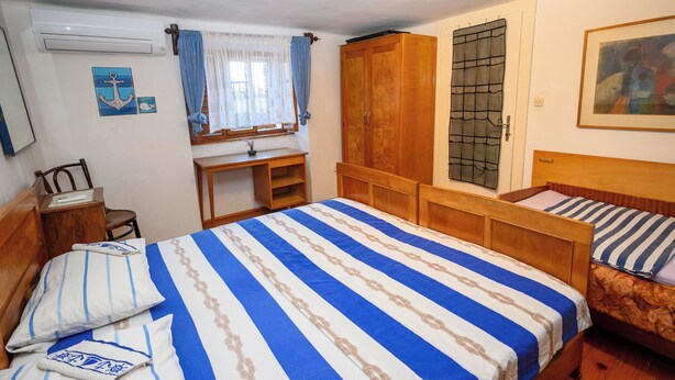 A bedroom with a bed, a desk, a chair, a wardrobe, and a window with curtains. - House Arija (Novi Vinodolski)