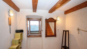 A room with a wooden staircase, a window with a view of a tiled roof, a wooden floor, and a wooden chair. - House Arija (Novi Vinodolski)