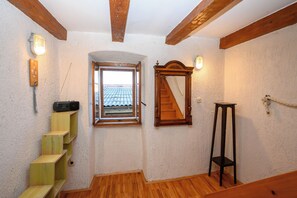 A room with a wooden staircase, a window with a view of a tiled roof, a wooden floor, and a wooden chair. - House Arija (Novi Vinodolski)