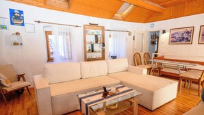 A cozy living room with a large sectional sofa, a wooden coffee table, and a dining area with chairs and a glass table. - House Arija (Novi Vinodolski)