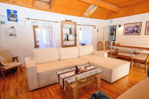 A cozy living room with a large sectional sofa, a wooden coffee table, and a dining area with chairs and a glass table. - House Arija (Novi Vinodolski)