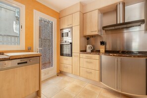 Eine moderne Küche mit Edelstahlgeräten, Holzschränken und einer Arbeitsplatte aus Granit.