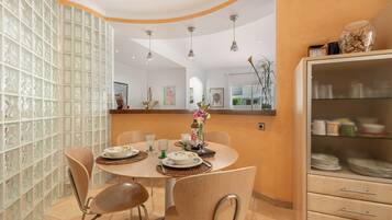 A dining area with a round table, chairs, and a cabinet with dishes.