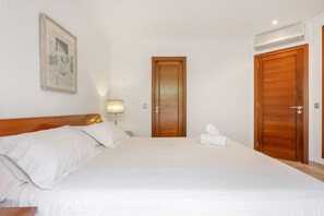 A hotel room with a large bed, a wooden door, and a framed picture on the wall. - Holiday Home 'Playa Y Relax' with Private Terrace, Wi-Fi and Air Conditioning (Can Picafort)